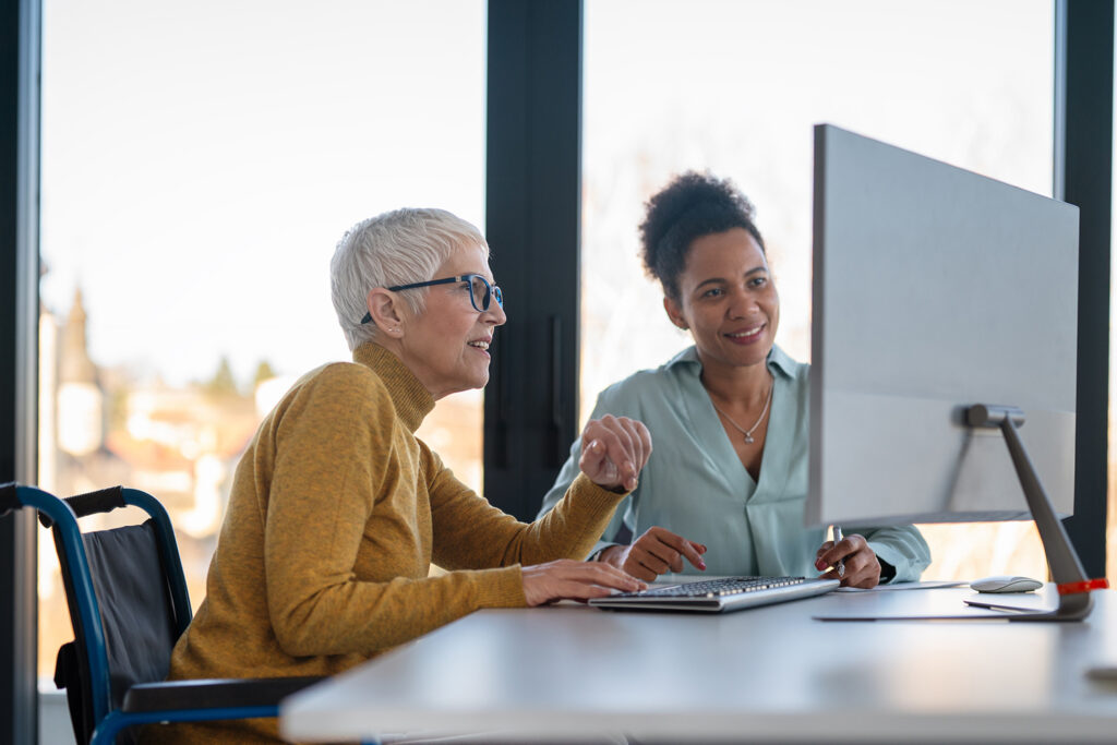 Business woman in wheelchair working with colleague in modern inclusive office.